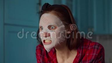 滑稽的30多岁的女人，脸上戴着白色化妆面具，在家里做鬼脸。 戴着蓝色面具做鬼脸的女人